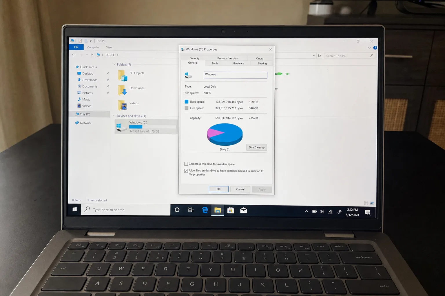 Laptop showing Windows C drive properties dialog with pie chart displaying 129GB used and 346GB free of 475GB capacity, file explorer open behind it