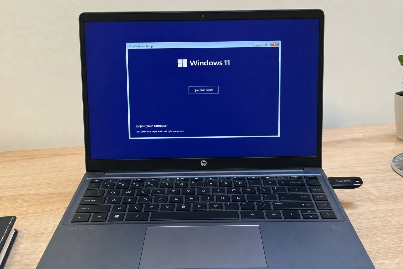HP Pavilion laptop showing Windows 11 Setup screen with Install now button and Repair your computer option, SanDisk USB drive plugged in